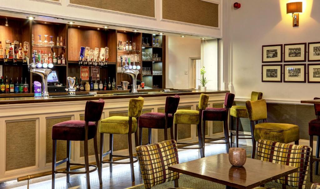 a bar with yellow and red chairs and a table at Best Western Thurrock Hotel in Grays Thurrock