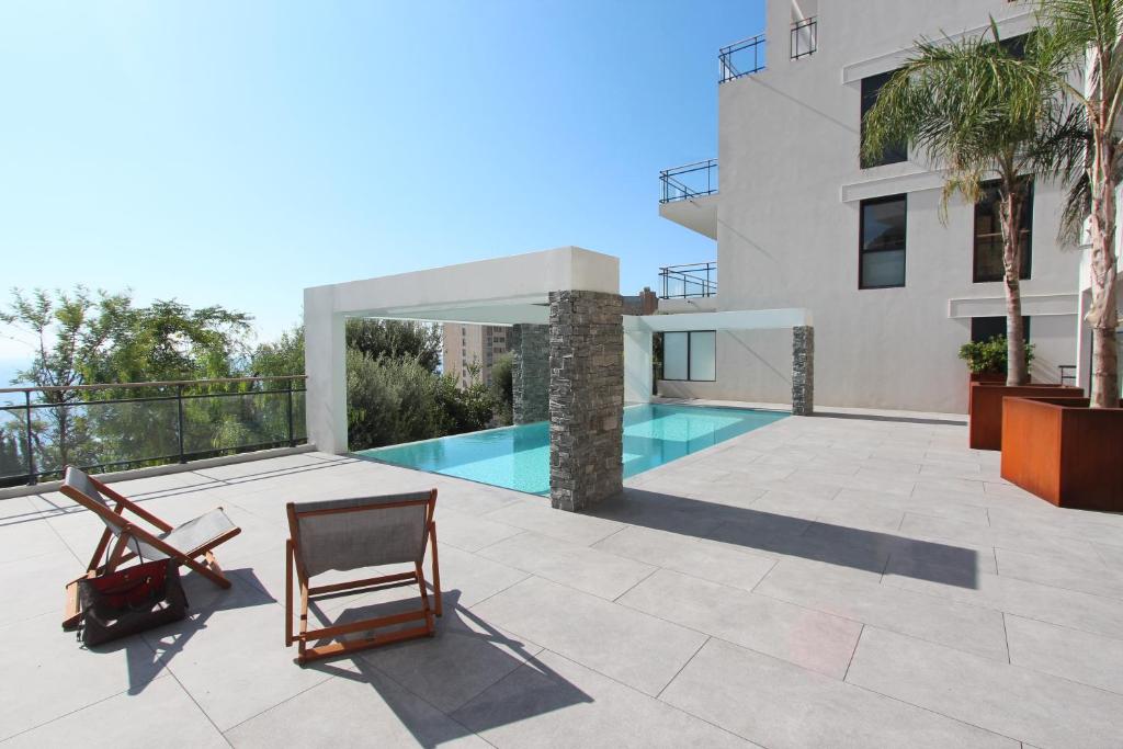 un patio con 2 sillas y una piscina en Luxurious Apartments Monaco&SeaView, InfinityPool&Parking, en Beausoleil