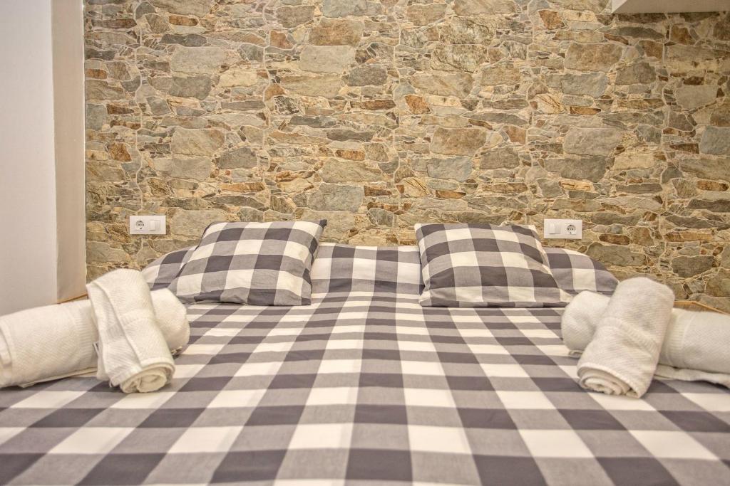 a bed with pillows in front of a stone wall at Casa Jerez Alameda del Banco in Jerez de la Frontera