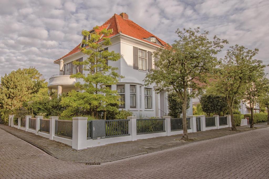 ein weißes Haus mit einem Zaun davor in der Unterkunft Hotel Haus Norderney in Norderney