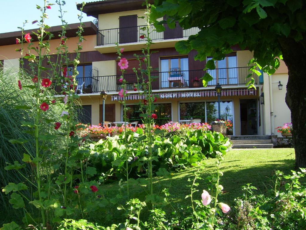 ogród przed budynkiem pełnym kwiatów w obiekcie Hôtel Les Pavillons du Golf w mieście Évian-les-Bains