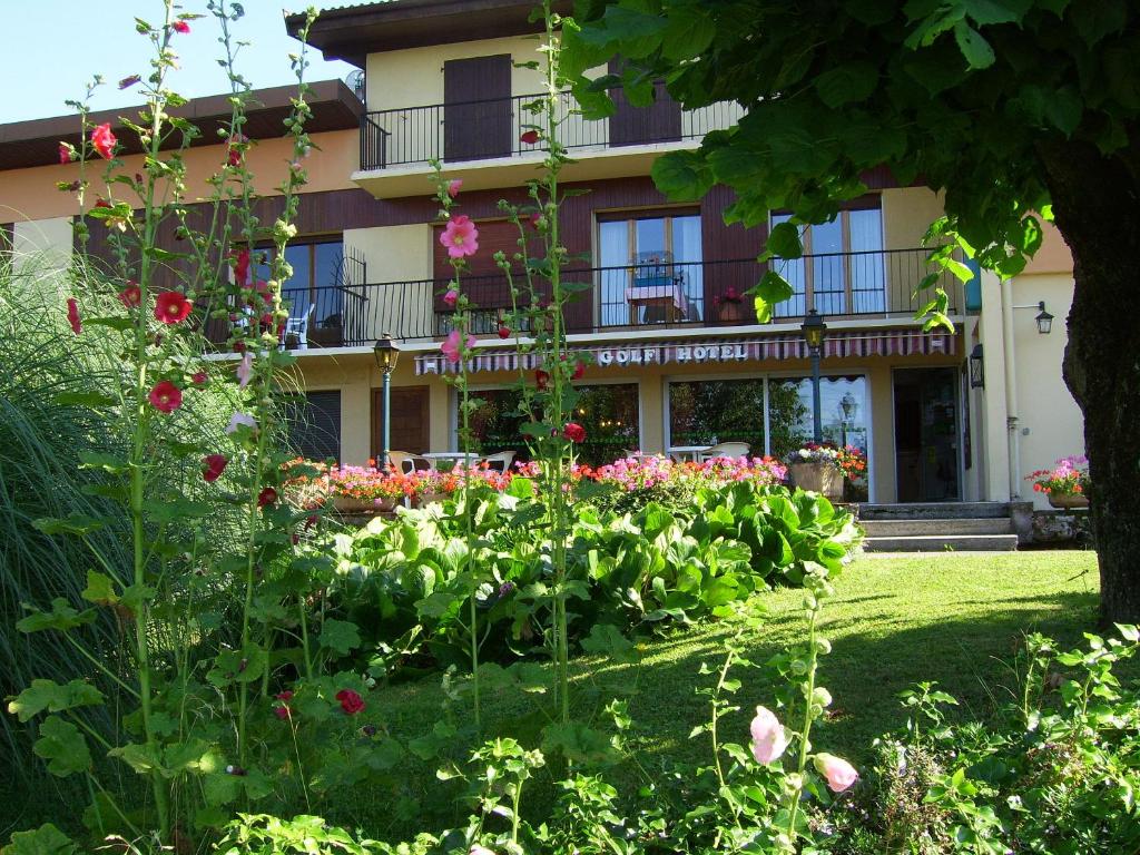 un jardín frente a un edificio con flores en Hôtel Les Pavillons du Golf en Évian-les-Bains