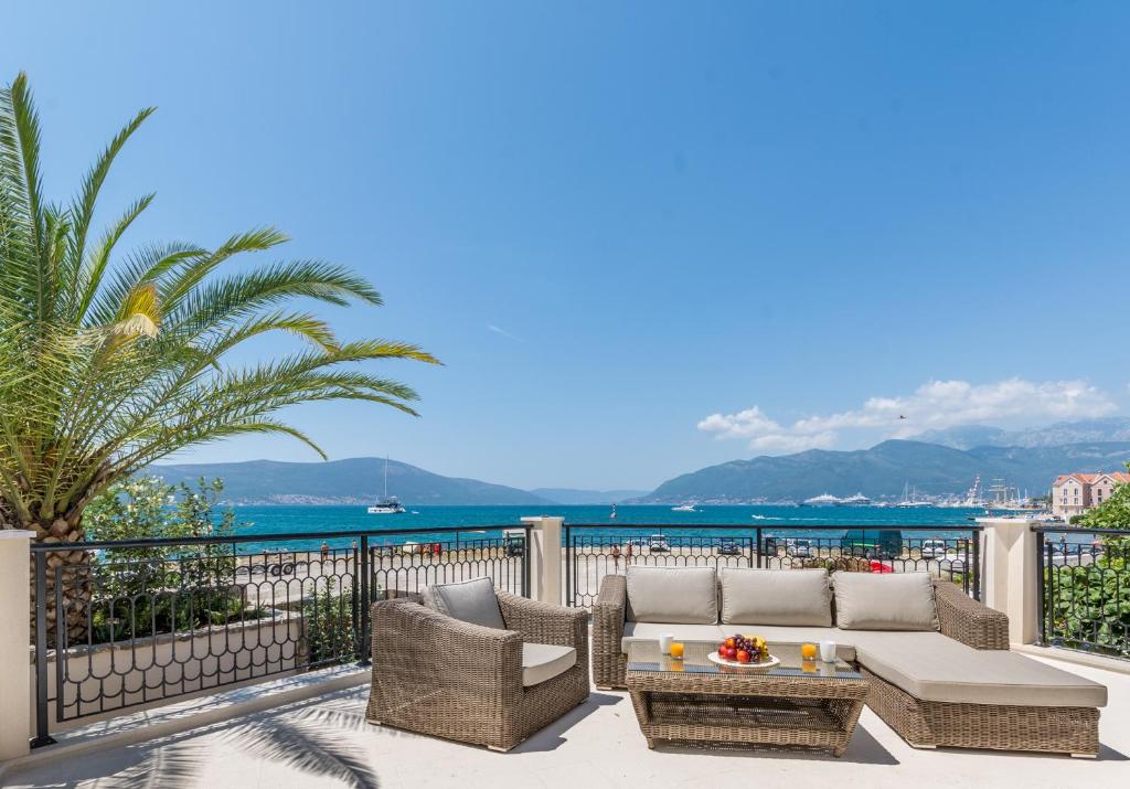 a patio with a couch and chairs and the ocean at Boka di Mare in Tivat
