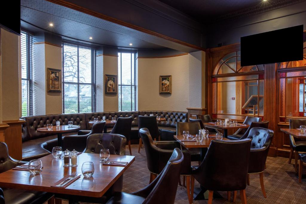 a restaurant with tables and chairs and a flat screen tv at Ferryhill House Hotel in Aberdeen