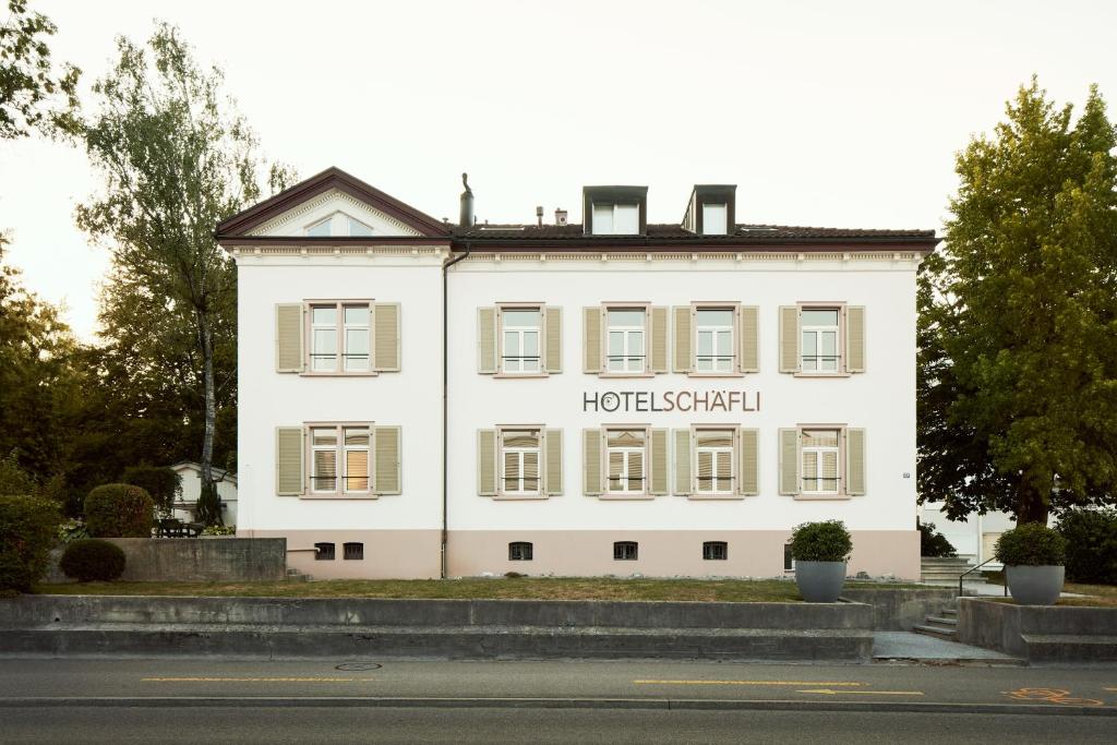 Ein weißes Gebäude mit einem Schild drauf. in der Unterkunft Hotel Schäfli in Uzwil