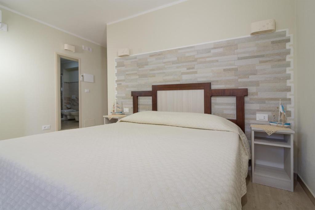 a bedroom with a white bed and a brick wall at La Cycas Accommodation in Tropea