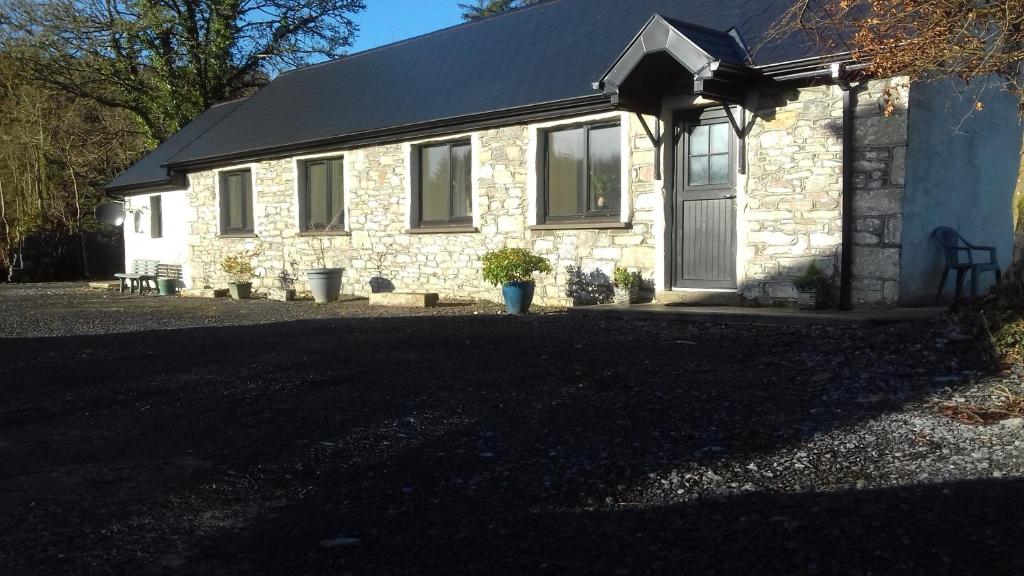 a stone house with a black roof at Ash Lodge Leitrim Village in Leitrim