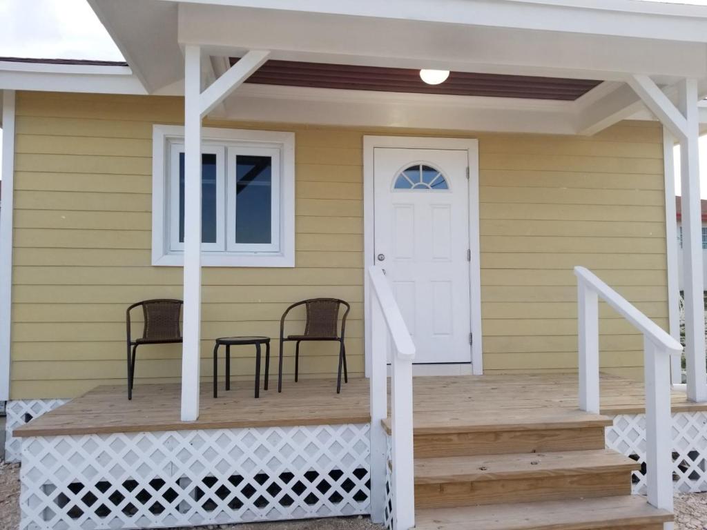 un porche con 2 sillas y una puerta blanca en SANDY BOTTOM COTTAGES en Mount Thompson