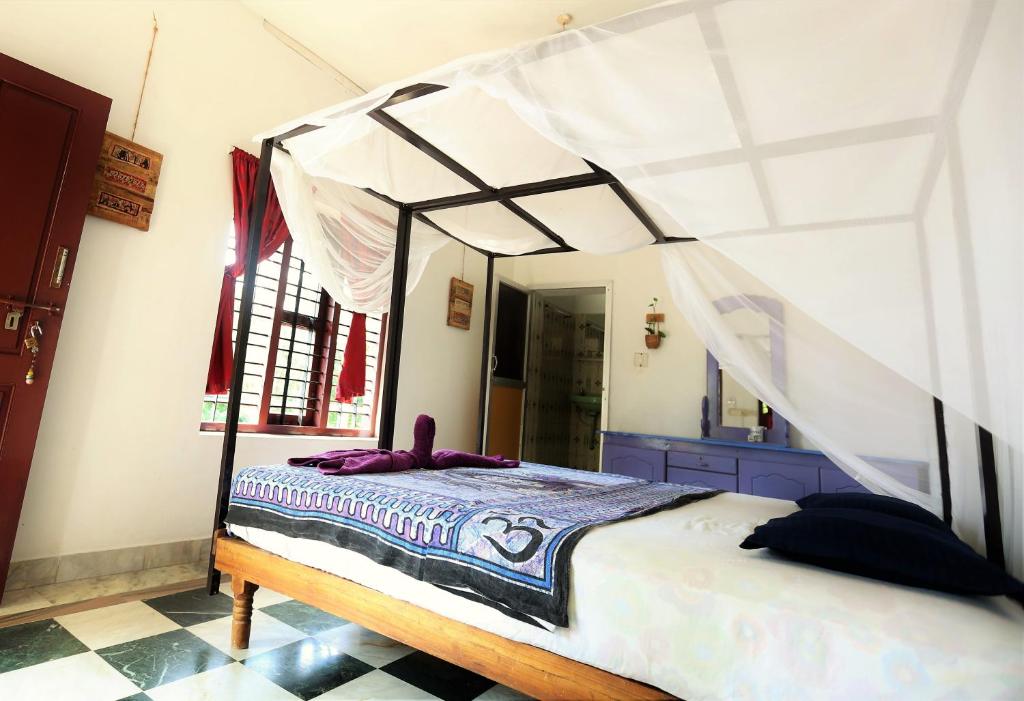 1 dormitorio con cama con dosel y espejo en Keratheeram Beach Resort, en Varkala