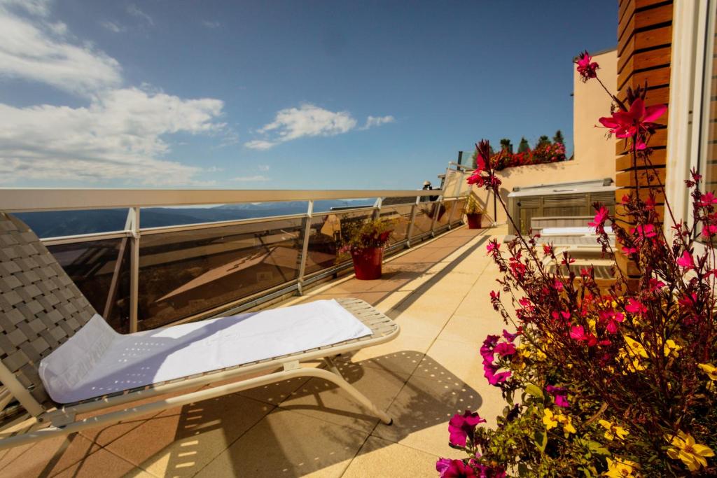 a balcony with a chair and flowers and the ocean at Le Grand Tétras in Font-Romeu