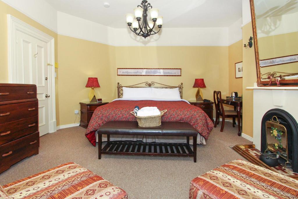 1 dormitorio con cama roja y chimenea en Abba Inn Guest House, en St. John's