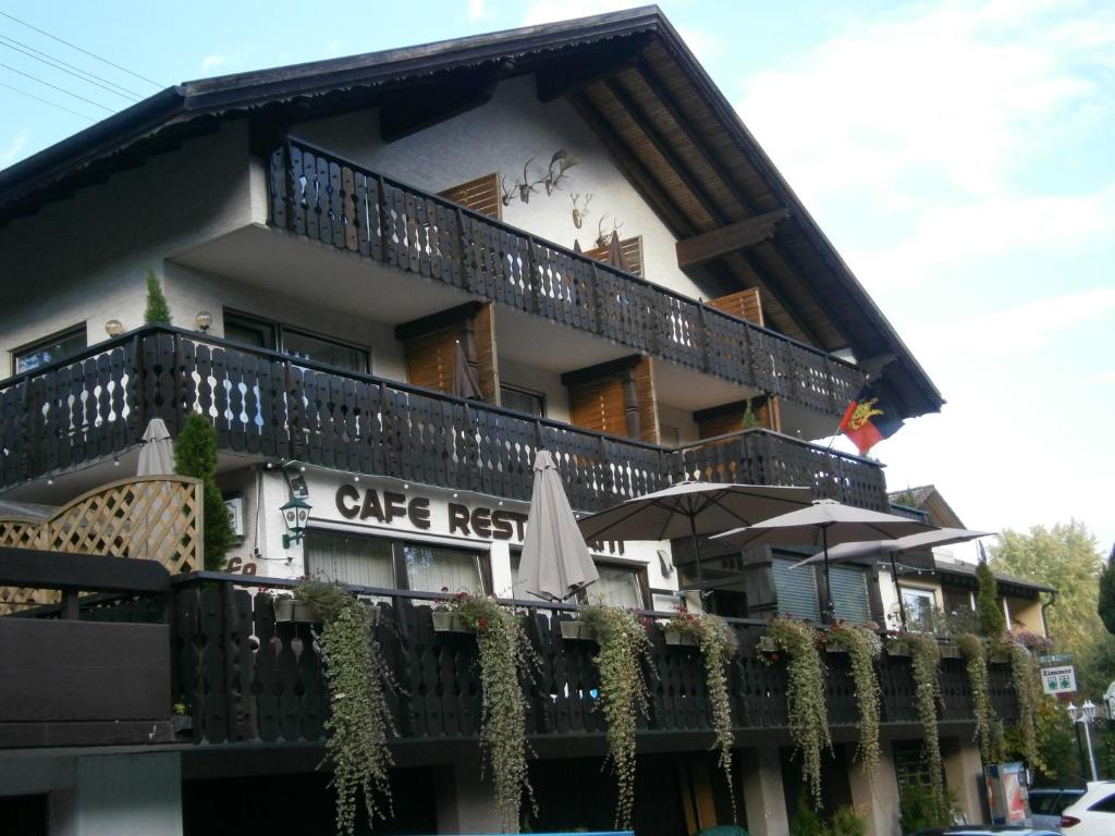 ein Gebäude mit einem Balkon und einem Sonnenschirm in der Unterkunft Hotel Waldsee in Waldachtal