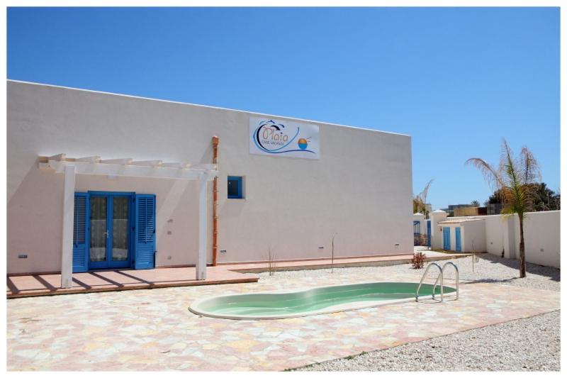 un edificio con una piscina verde frente a un edificio en Plaia Case Vacanza, en Favignana
