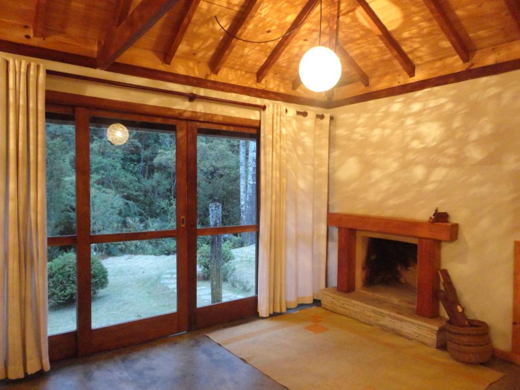 uma sala de estar com lareira e uma grande janela em Estalagem Engenho de Serra em Itamonte