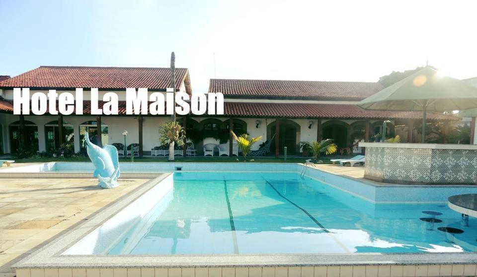 um hotel com piscina em frente a um edifício em Pousada La Maison em Iguaba Grande