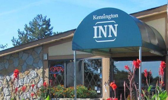 a restaurant with a blue umbrella in front of a building at Kensington Inn - Howell in Howell