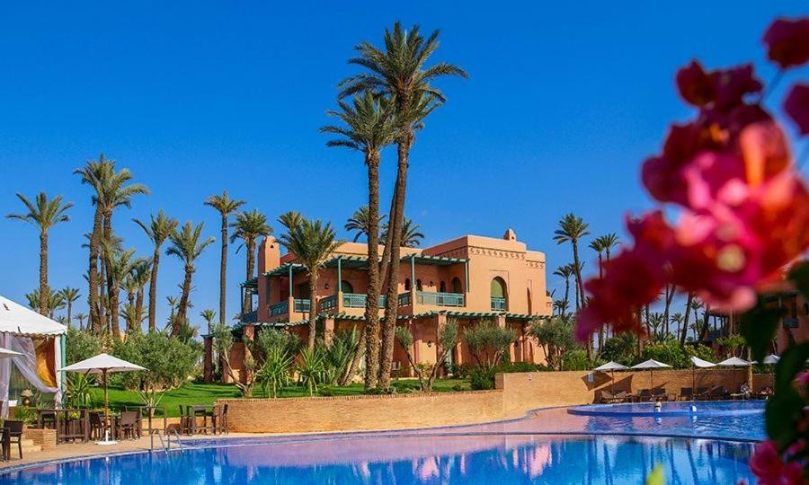 a resort with a large swimming pool and palm trees at la palmeraie village Appartement in Marrakesh