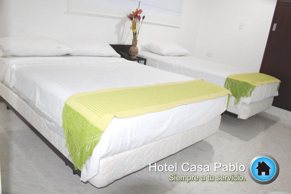 a bedroom with two beds with white sheets at Hotel Casa Pablo in Neiva