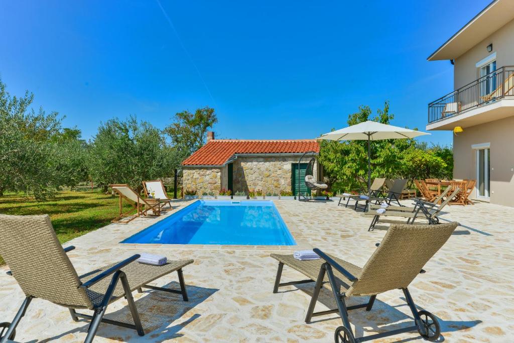 a villa with a swimming pool and chairs at Holiday Home M&M in Benkovac