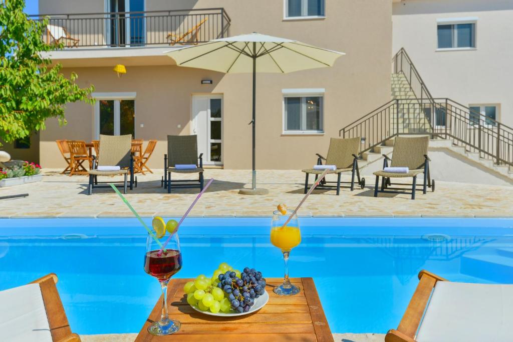 a table with fruit and drinks next to a swimming pool at Holiday Home M&M in Benkovac