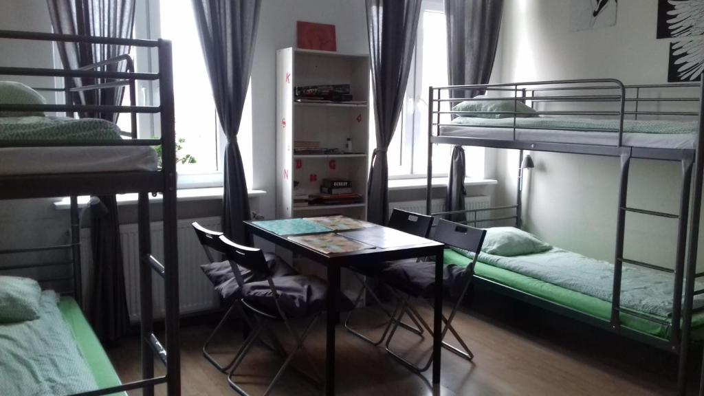 a room with bunk beds and a table and chairs at Art Hostel in Kraków