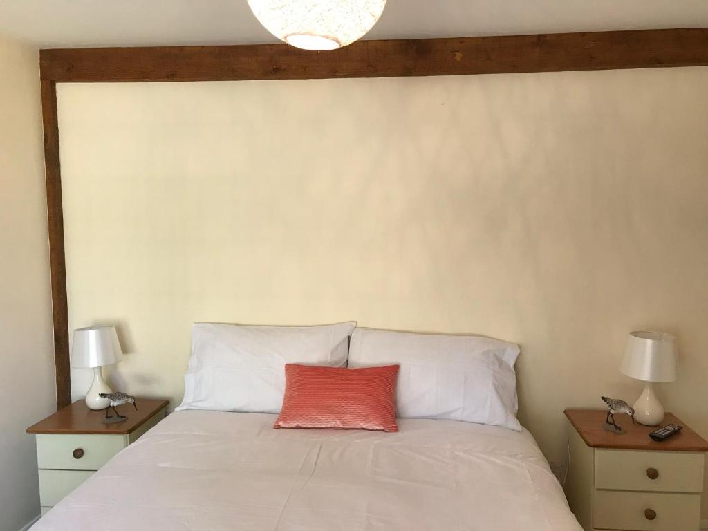 a bedroom with a white bed with a red pillow at Windmill Cottage in Worthing