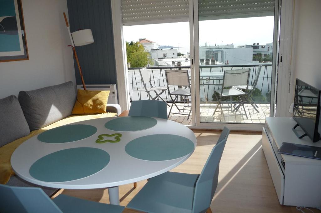 uma sala de estar com uma mesa e cadeiras e uma varanda em Le balcon de la Conche em Royan