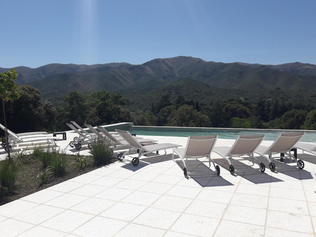 un grupo de tumbonas y una piscina en Huerta Grande Cabañas en Huerta Grande