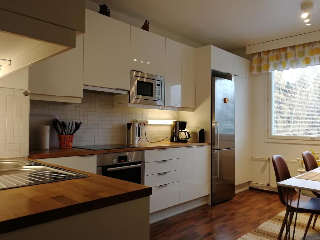 a kitchen with white cabinets and a counter top at Sun Apart Vuorenrinne in Kotka