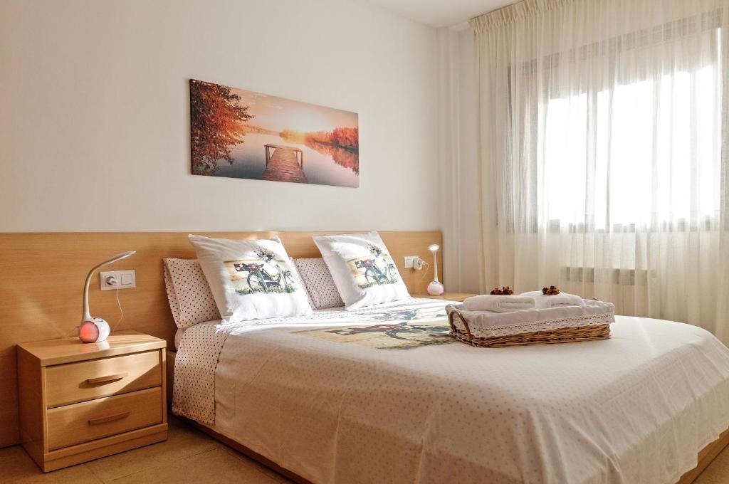 1 dormitorio con 1 cama con colcha blanca y ventana en Apartamento "El Lilà 2" - Parking incluido, en Girona