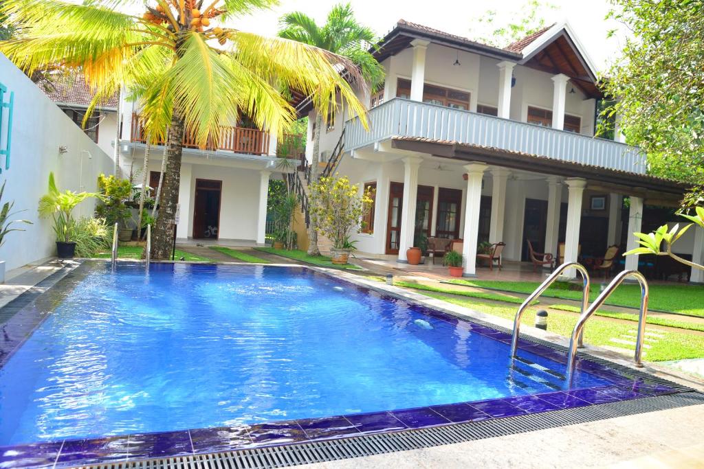 a swimming pool in front of a house at Surf Villa in Hikkaduwa