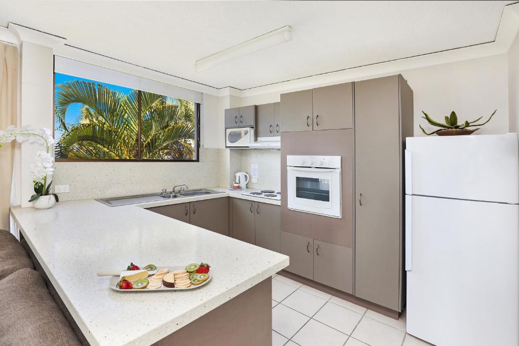 a kitchen with a counter and a white refrigerator at Headland Tropicana Resort in Alexandra Headland