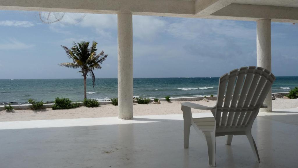a chair sitting on a porch looking at the beach at Rancho Sakol in Puerto Morelos