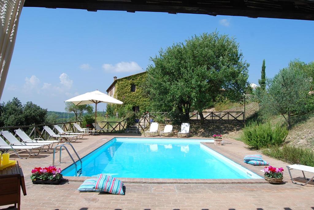 a swimming pool with chairs and a house at Podere Costa Romana in Narni