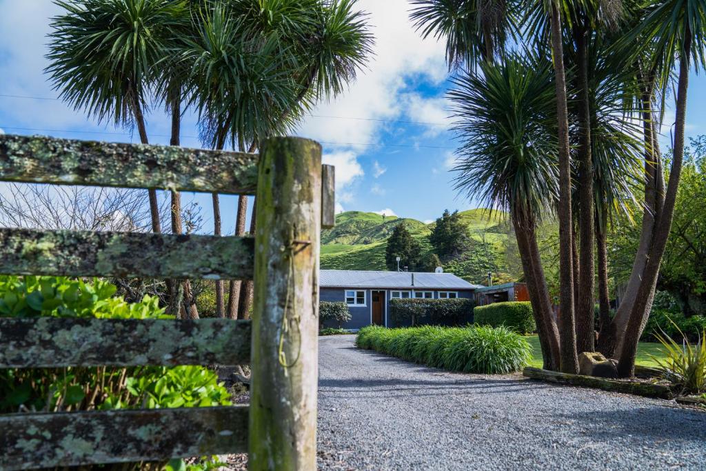 una recinzione di fronte a una casa con palme di Mahaanui Cottage Farmstay a Tiniroto
