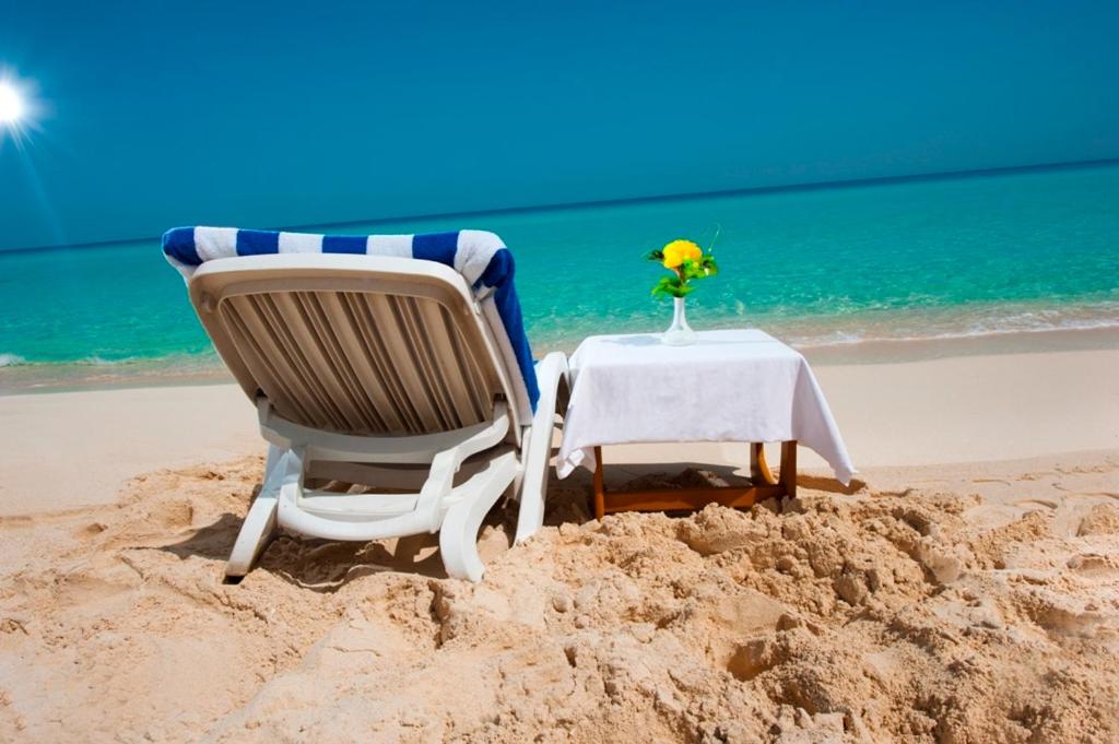 una mesa y sillas en la arena de la playa en Aida Beach Resort Serviced Apartments, en El Alamein
