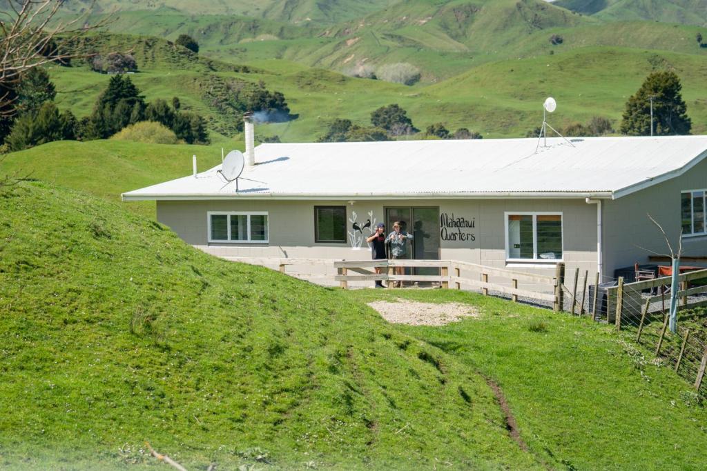 ein Haus auf einem Hügel mit zwei Leuten, die in der Tür stehen in der Unterkunft Mahaanui Quarters Farmstay in Tiniroto