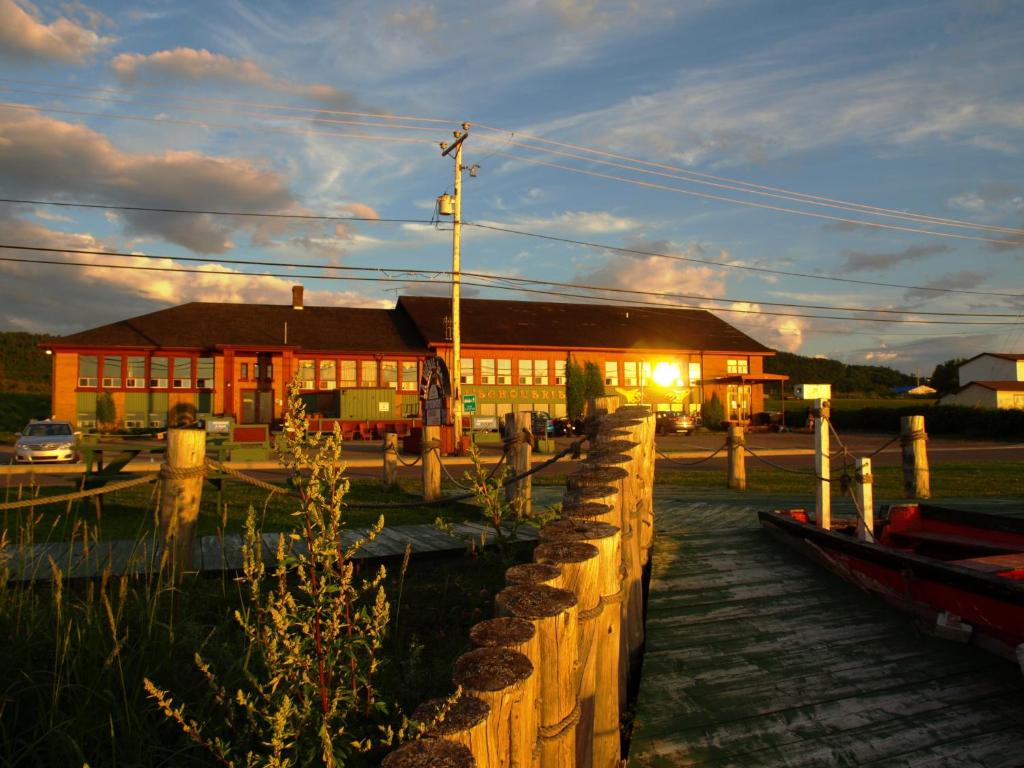 a building with a dock with boats in front of it at Auberge Internationale La Vieille École in Sainte-Anne-des-Monts