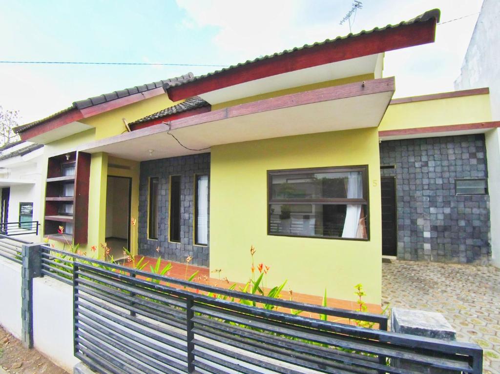 een geel huis met een zwart hek ervoor bij The Batu Villas No 5 in Batu
