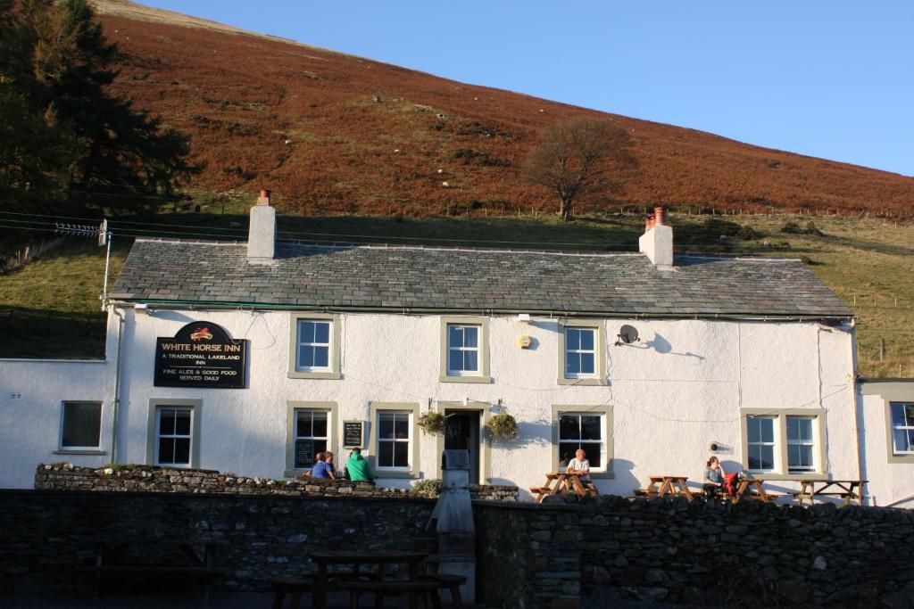 a white building with people sitting outside of it at The White Horse Inn Bunkhouse in Threlkeld