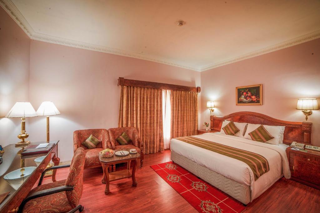 1 dormitorio con cama, silla y escritorio en Raj Park Hotel Chennai, en Chennai