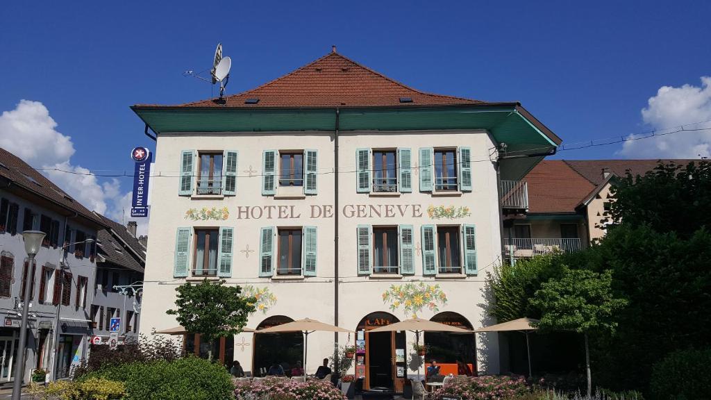 ファヴェルジュにあるHôtel de Genève et Restaurant , Faverges-SeythenexのホテルのDMGガレージ付きの白い大きな建物