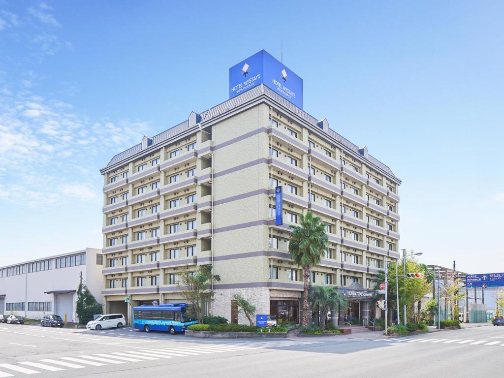 a large white building with a blue sign on top of it at HOTEL MYSTAYS Maihama in Urayasu