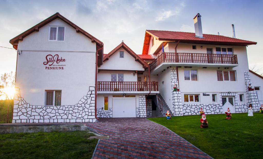 a large white house with a red roof at Pensiunea SilvAnka in Vîlcele