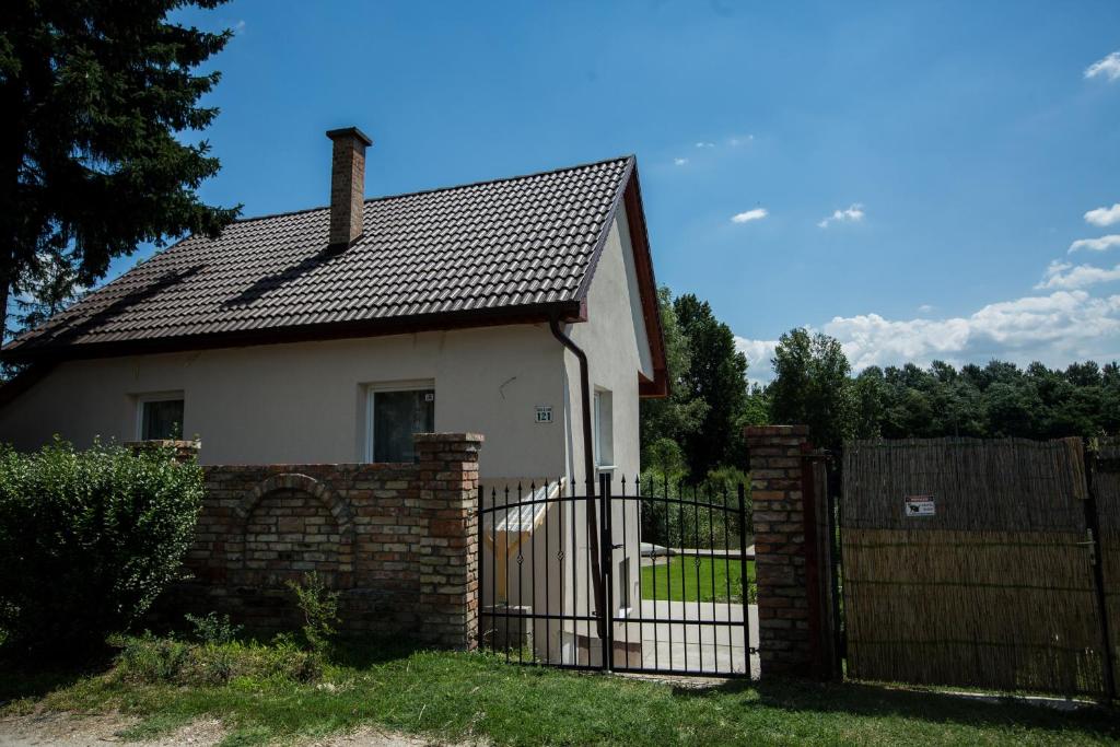 una pequeña casa blanca con una puerta y una valla en Vendégház az Evezőhöz, en Szigetszentmiklós
