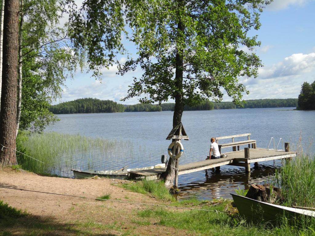 a person sitting on a dock on a lake at Isotalo Farm at enäjärvi lake in Salo