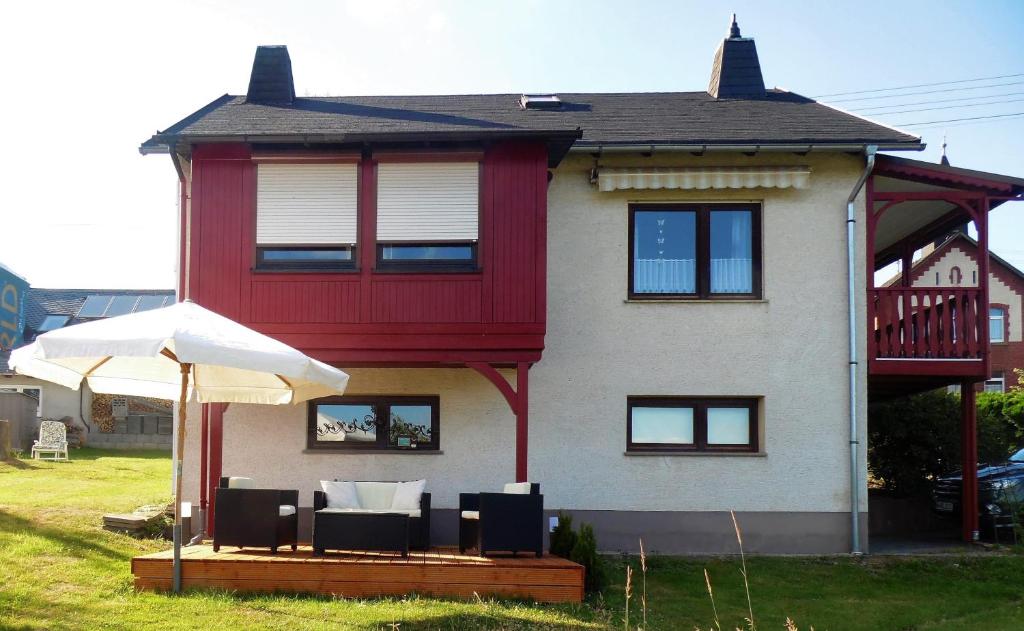 uma casa com cadeiras e um guarda-sol em frente em Ferienhaus zur schönen Aussicht em Hardt