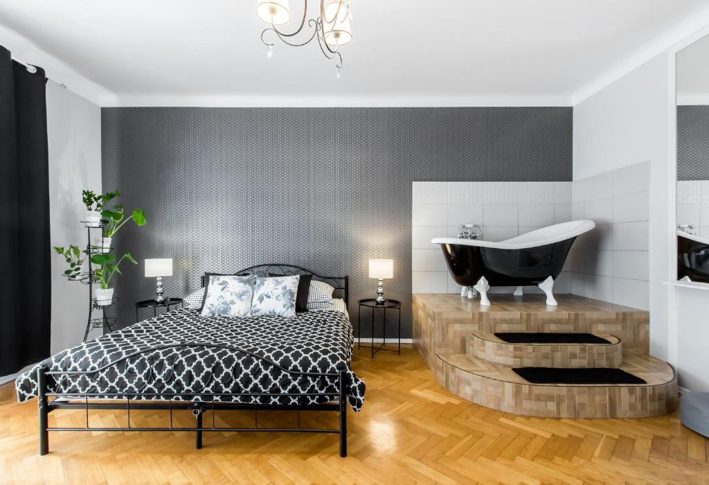 ClickTheFlat Apartment Chmielna 7 في وارسو: غرفة نوم مع سرير وحوض استحمام