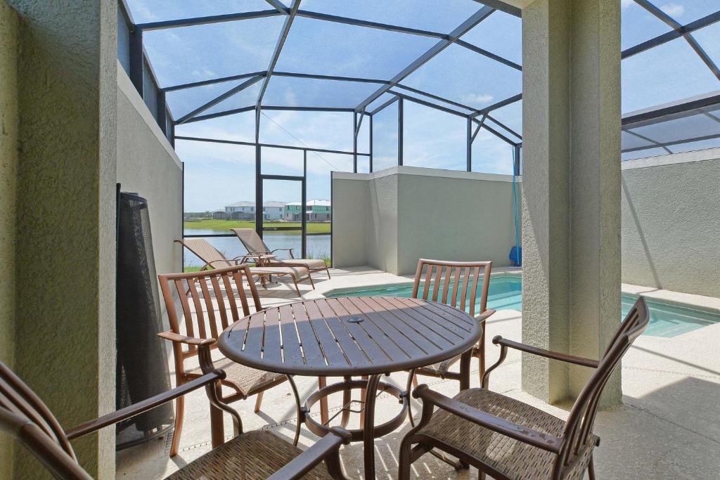 un patio con mesa, sillas y piscina en Storey Lake-5 Bedroom Townhouse w/Splashpool-1617ST, en Kissimmee
