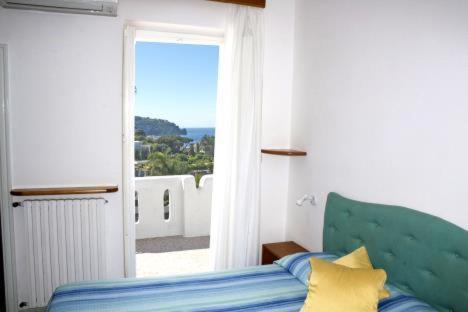 una camera con letto e porta di accesso a un balcone di Hotel Parco Conte a Ischia